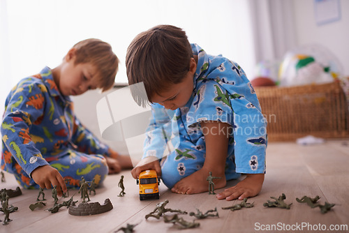 Image of Boys, playing and children in pajamas with toys for fun with action figures, car or games. Brothers, child development and young kids bonding together in playroom for learning at family home.
