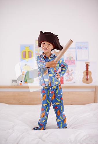 Image of House, portrait or costume as pirate to play in fantasy in a home with telescope toy or smile. Kid sailor, child captain or happy boy in a game with pyjamas, hat or creative monocular to sail on bed