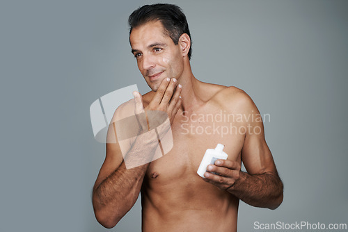 Image of Man, moisturizer and skincare lotion in studio for hygiene treatment for facial wellness, grey background or mockup space. Male person, product and healthy dermatology for anti aging, cream or apply
