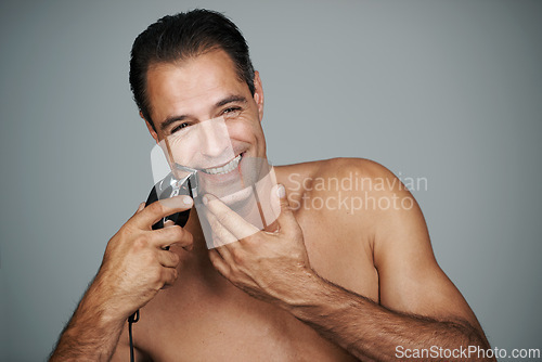 Image of Man, portrait and smile with electric razor or beard grooming in studio for skincare trimmer, self care or grey background. Male person, shave and hair removal tool or hygiene, health or mockup space