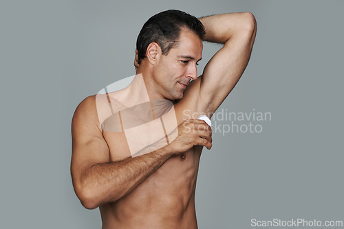 Image of Skincare, man and deodorant for hygiene in studio, cosmetics and body in gray background. Male person, daily routine and clean armpit for odor or fresh, confident or pride and smile in mockup space