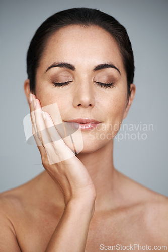 Image of Beauty, mature and skincare of woman touching face with makeup at studio isolated on gray background. Cosmetics, glow and hand of model in facial treatment for dermatology, anti aging and eyes closed