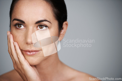 Image of Face, skincare and mature woman in makeup at studio isolated on a gray background mockup space. Cosmetics, hand and female model in touching skin for dermatology, beauty and thinking of anti aging