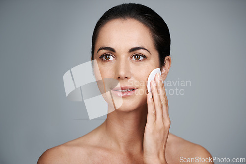 Image of Mature woman, pad and clean in studio, skin care and facial treatment on gray background. Female person, cotton and swab for grooming in daily routine, mockup space and dermatology to remove makeup