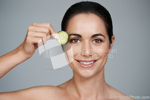 Image of Portrait, beauty and cucumber with smile of woman in studio on gray background for natural wellness. Face, antiaging or detox and happy mature model with vegetable slice for diet, health or nutrition