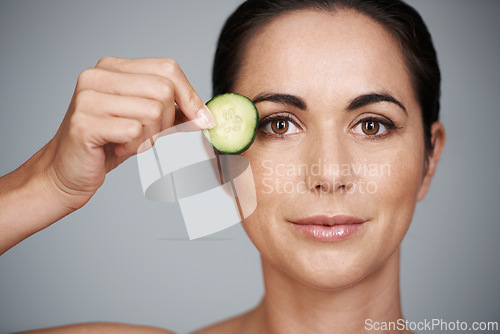 Image of Portrait, beauty and cucumber for detox with woman in studio isolated on gray background for wellness. Face, skincare or antiaging routine and mature person with slice of fruit for dermatology