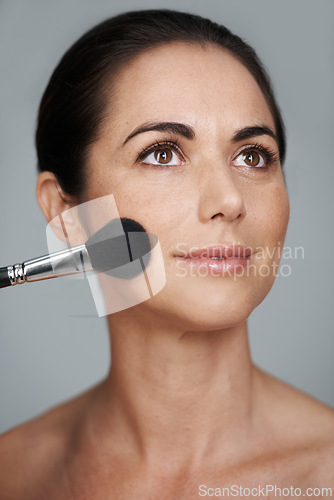 Image of Cosmetics, brush and mature woman in studio with beauty, natural and facial glow routine. Makeup, self care and confident female person with cosmetology tool for glow isolated by gray background.