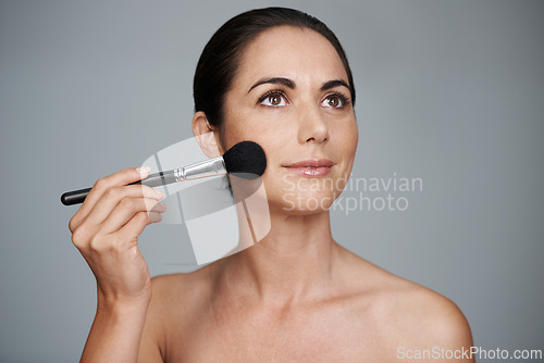 Image of Makeup, brush and mature woman in studio with beauty, natural and facial glow routine. Cosmetics, self care and confident female person from Canada with cosmetology tool isolated by gray background.