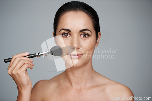 Image of Beauty, brush and portrait of woman in studio with makeup, natural and facial glow routine. Cosmetics, self care and confident mature female person with cosmetology tool isolated by gray background.