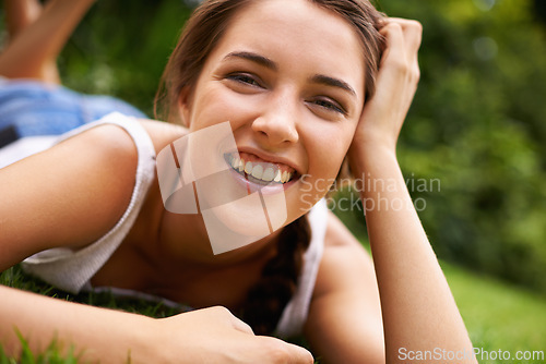 Image of Woman, portrait and laughing on grass for relax with sunshine, enjoyment or weekend break in summer. Young person, funny and confident on lawn, garden or backyard of home for fresh air in environment
