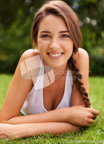 Image of Woman, portrait and smile on grass for relax with sunshine, enjoyment or weekend break in summer. Young person, happiness or confident on lawn, garden or backyard of home for fresh air in environment