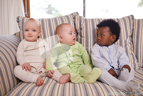 Image of Living room, diversity and baby friends on sofa in home together for morning child development. Adorable, cute or innocent with boy and girl infant kids in onesie pajamas at apartment for bonding