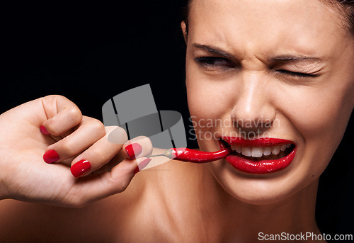 Image of Beauty, makeup and woman eating chilli in studio with manicure on hand isolated on a black background. Cosmetics, model and person with pepper in mouth, food or healthy vegetable for skincare on face