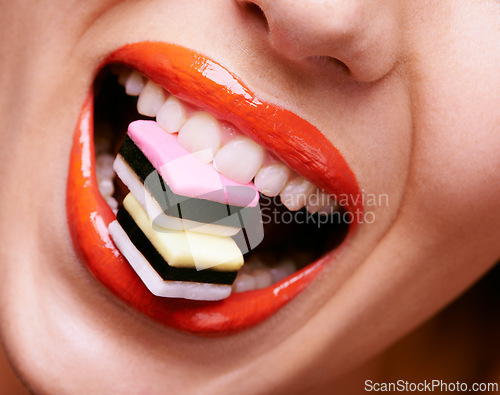 Image of Beauty, lipstick and woman with candy in mouth, makeup and creativity with closeup of shiny cosmetic product. Licorice, sweets and orange lip gloss for aesthetic, art and cosmetology with glamour