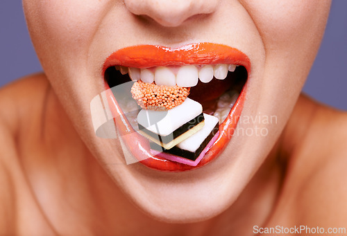 Image of Makeup, lipstick and woman with sweets in mouth, beauty and creativity with closeup of shiny cosmetic product. Licorice, candy and orange lip gloss for aesthetic, art and cosmetology with glamour
