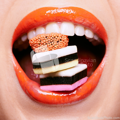 Image of Closeup, lipstick and woman with candy in mouth, makeup and creativity with shiny cosmetic product for beauty. Licorice, sweets and orange lip gloss for aesthetic, art and cosmetology with glamour