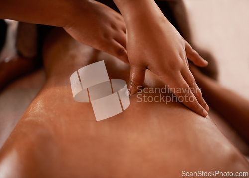 Image of Back, hands, and client with massage, spa and stress relief with luxury and wellness with hospitality industry. People, masseuse and customer on a table, hotel and vacation with treatment or grooming