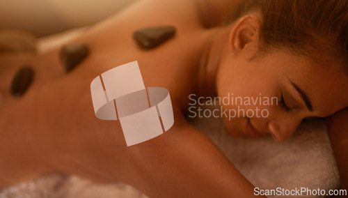 Image of Woman, relax and stone therapy at spa for muscle healing, back pain or luxury body care in hotel. Female person, happy and zen with peace for holistic treatment, organic healthcare and body recovery