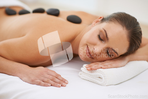 Image of Relax, hot stone massage and woman on bed at spa for health, zen wellness and luxury holistic treatment. Self care, peace and girl on table for body therapy, comfort and calm pamper service at hotel