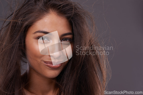 Image of Portrait, confident woman or messy hair in wind, damage or treatment in studio on grey background. Grooming, frizz and tangle in simple keratin female model for dull and dry texture and scalp