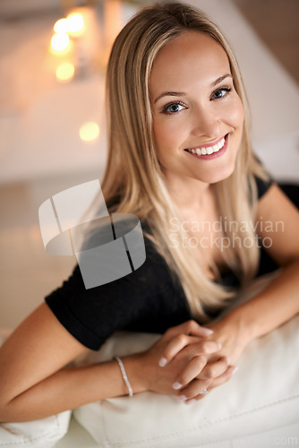 Image of Portrait, woman and smile on couch in living room, wellness and candles for peace in apartment. Face, positive and blonde lady to relax on sofa, mindfulness and tranquility on weekend night in home