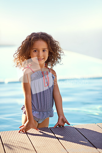 Image of Child, girl and water with portrait, swimsuit and blue summer sky for relax or smile. Kid, youth and sunshine with happiness, outdoor and play with curly hair and fun or sunny positivity or childhood