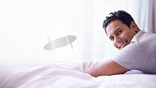 Image of Man, smile and portrait on bed for happy and relax at home or indoor on weekend and alone. Young person, attractive or handsome for unwind, rest or chill in apartment on mattress inside South Africa