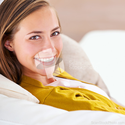 Image of Closeup, portrait and woman in house, home and apartment to relax on sofa, couch and smile for happiness. Female person, confidence and gen z girl in lounge, living room and residence for time off