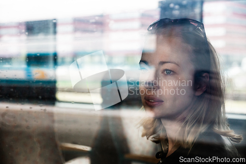 Image of Woman traveler contemplating outdoor view from window of train. Young lady on commute travel to work sitting in bus or train.