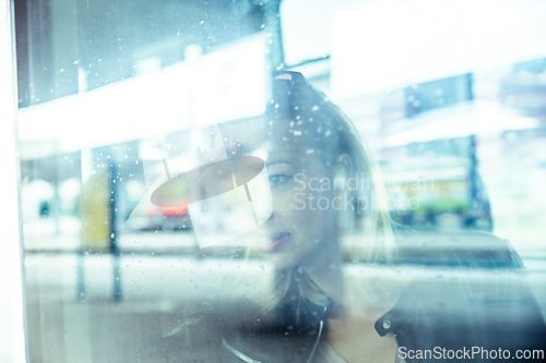 Image of Woman traveler contemplating outdoor view from window of train. Young lady on commute travel to work sitting in bus or train.