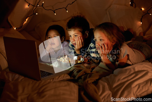 Image of Children, laptop and watch in tent at night with movies, film or cartoons for holiday adventure or vacation. Young boy, girl or kids with lights, pillows and blanket at home on computer for Netflix