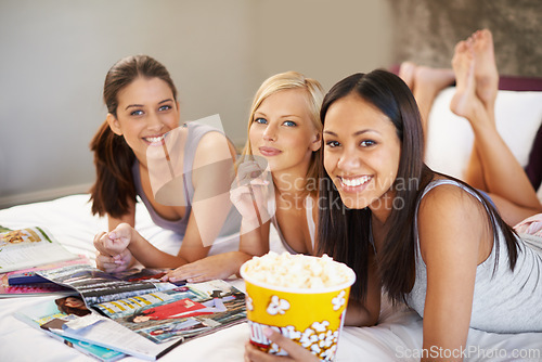 Image of Friends, popcorn and portrait for sleepover, social and bedroom for bonding and excited group for snacks. Female people, together and magazines for jokes, besties and entertainment with conversation