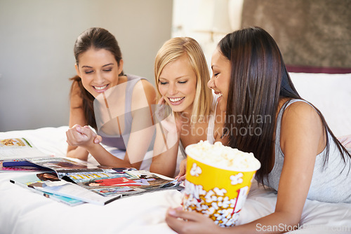Image of Friends, popcorn and reading for sleepover, social and bedroom for bonding and excited group for snacks. Female people, together and magazines for jokes, besties and entertainment with conversation