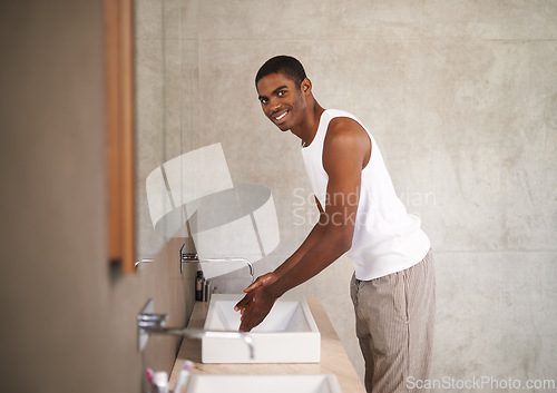 Image of Bathroom, sink and black man washing of hands, portrait and smile for cleaning with water from tap. Health, hygiene and male person happy with protection from bacteria, germs and viruses with liquid