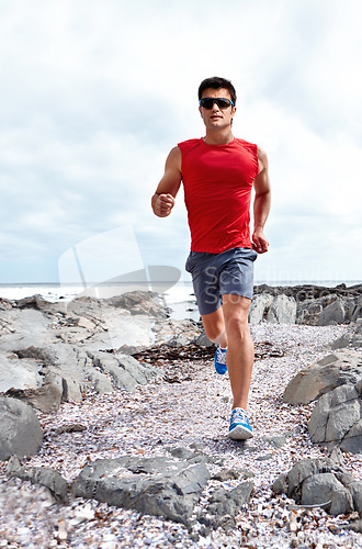 Image of Athlete male person, running and beach for fitness, health and wellness in activewear and sunglasses. Man, jog and seaside for sport, training and workout exercise for cardio outdoor routine