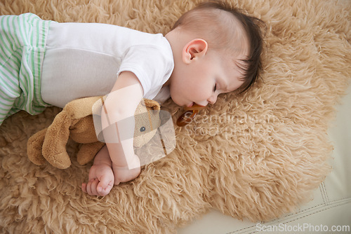 Image of Toddler, sleep and home with teddybear in sofa to rest, tired and relax with dummy and dream. High angle, baby, and nap in couch for child development, growth and innocent with peace for bedtime.