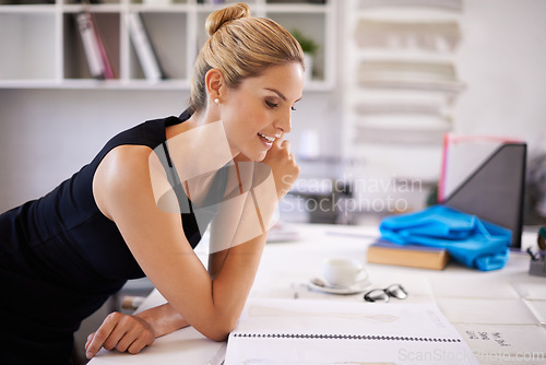 Image of Fashion designer, woman and sketch for ideas, production and brainstorming at her desk in workshop. Young worker, tailor or artist with book or drawing for clothes, manufacturing and textile business