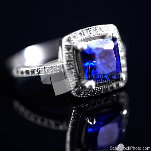 Image of Sapphire, silver ring and studio by black background for closeup, vintage product and luxury. Tanzanite, blue gemstone and white gold with precious metal for jewelry, shine and glow with reflection