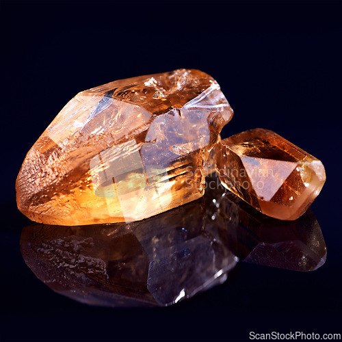 Image of Orange stone, jewel studio by black background for natural resource, garnet or sparkle for luxury. Rock, gemstone or crystal in closeup for shine, glow and uncut mineral with reflection for wealth