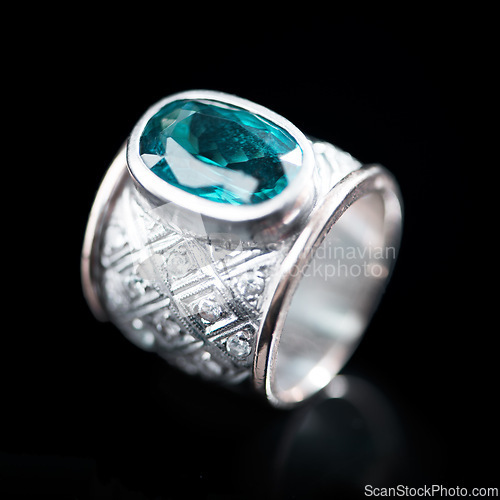 Image of Green, silver and ring on a black background for luxury gift, expensive and engagement or marriage in studio. Jewelry, diamonds and gemstone or rock in closeup with product texture and emerald color