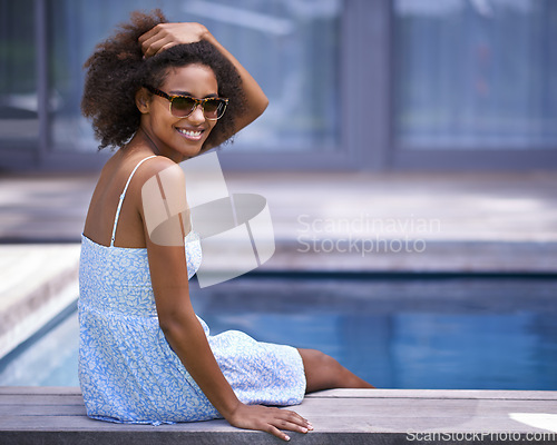 Image of African woman, outside and pool for vacation in summer, sitting and happy for trip with sunglasses. Holiday for relax and casual for swimming and happiness for wellness with natural female model