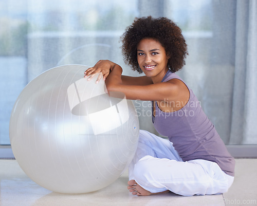 Image of Woman, portrait and exercise ball for fitness and wellness in studio or home for balance and health on the floor. Happy and young African person with workout, pilates and relax on ground for break