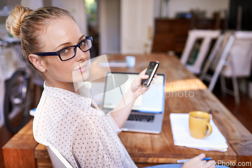 Image of Woman, phone and laptop on table in home office for remote work, startup and text online with coffee.Young person and smile with tech for internet, research and scroll for message indoor on blurred