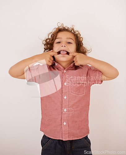 Image of Boy, kid and portrait in studio with tongue out for funny face, joke or games by white background. Child, mouth and comic gesture with fashion, playful and emoji with trendy style, shirt or clothes