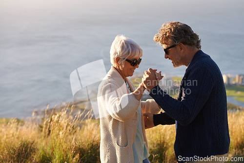 Image of Happy, couple and dance outdoor on holiday, holding hands with love and relax on hill or mountain in Cape Town. Mature, people and embrace with kindness on vacation adventure in nature together