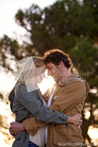 Image of Outdoor, hug and couple with love, sunshine and happiness with romance and cheerful in a park. People, embrace and woman with man or date with marriage or relationship with sunset or bonding together