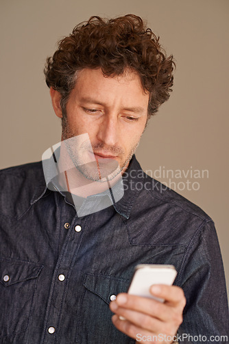 Image of Mature man, phone and texting in studio for thinking, reading or scroll for search on web by background. Person, smartphone and check for email, notification or post on social network with mobile app
