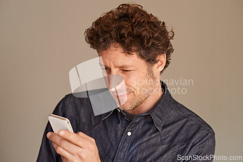 Image of Mature man, smartphone and texting in studio for thinking, reading or scroll for search on web by background. Person, phone and check for email, notification or post on social network with mobile app