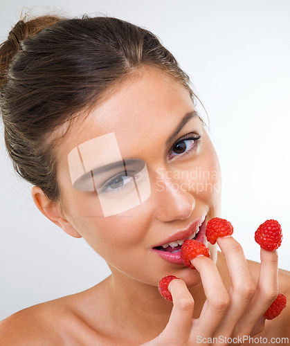 Image of Woman, portrait and raspberry for health in studio for wellness detox, healthy eating and nutrition diet. Model, person and fruit for organic cosmetics, natural beauty or skincare on white background