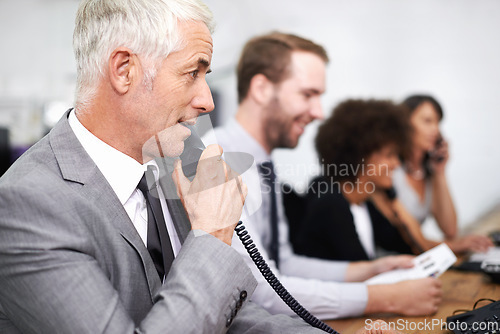 Image of Call center, man and landline in office for customer service with telemarketing, help desk and conversation. Senior, employee and face of consultant with telephone for support, telesales and advice